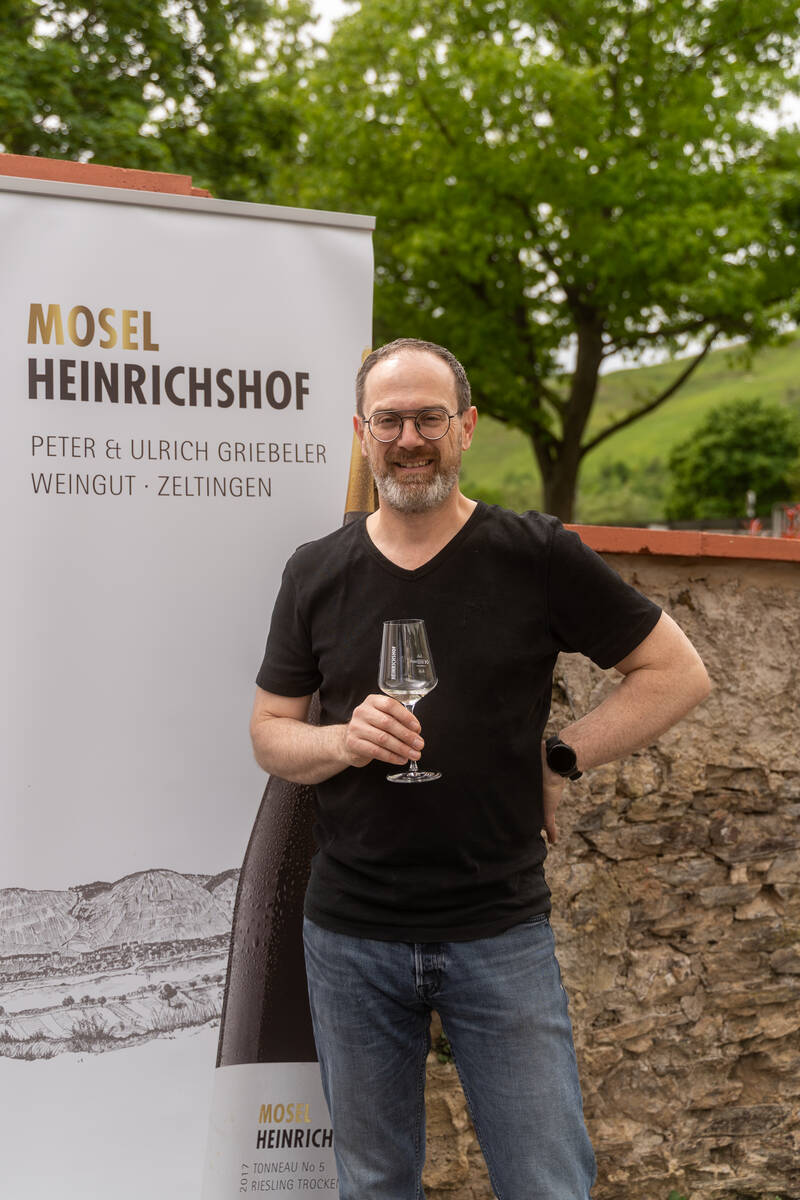 Der Winzer vom Heinrichshof steht vor seinem Roll-Up und lächelt in die Kamera.