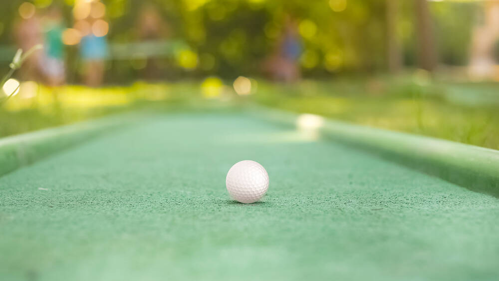 Ein Minigolfball liegt auf der grünen Minigolfanlage.