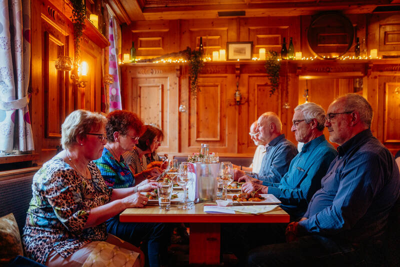 Mehrere Erwachsene sitzen an einem schick gedeckten Tisch und genießen ihr Essen.