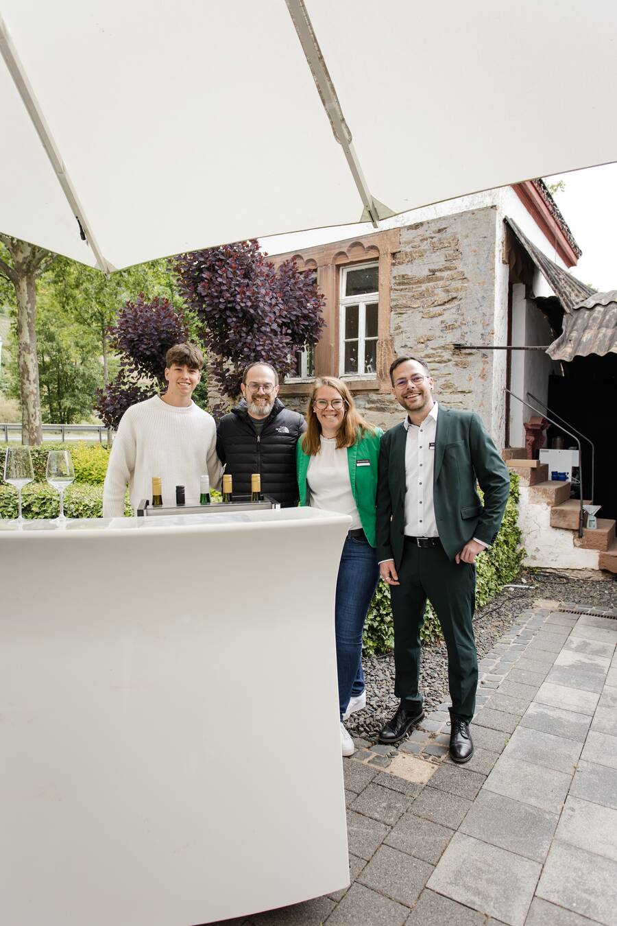 Die beiden Hotelchefs stehen neben einem der Winzer und lachen gemeinsam in die Kamera.