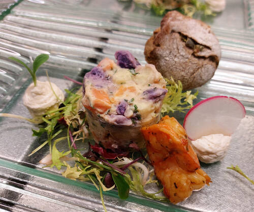 Terrine aus drei verschiedenen Kartoffelsorten, serviert mit einer Garnele und fein geschnittenen Radieschen.