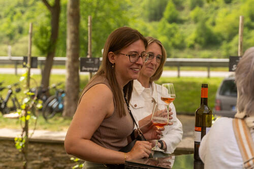 Zwei Gäste stehen beisammen und trinken ein Glas Rosé.