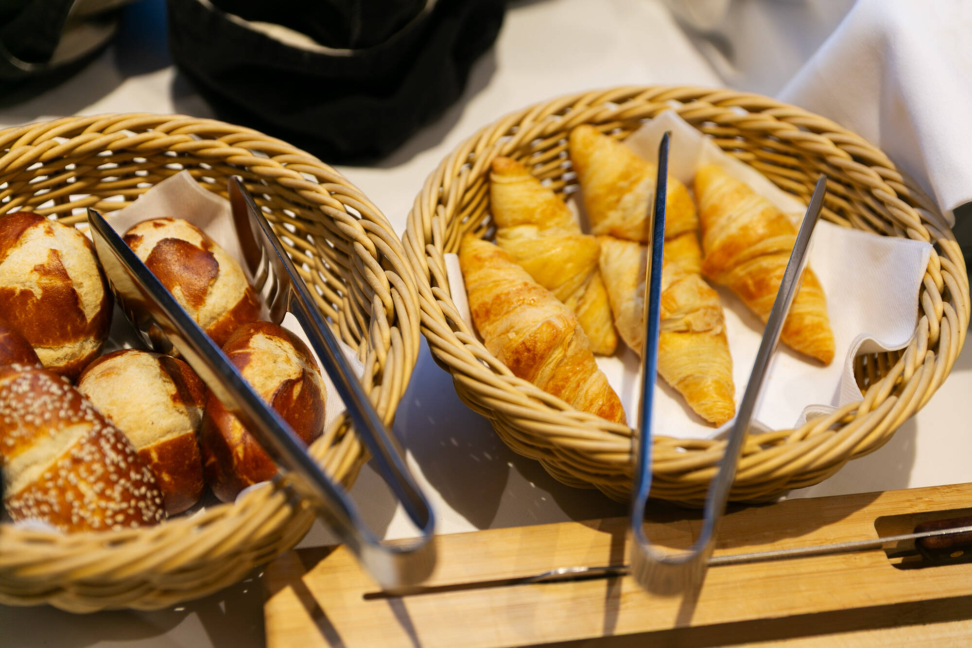 Auf dem Frühstücksbuffet sind in zwei Körbchen kleine Laugengebäcke und Croissants angerichtet.