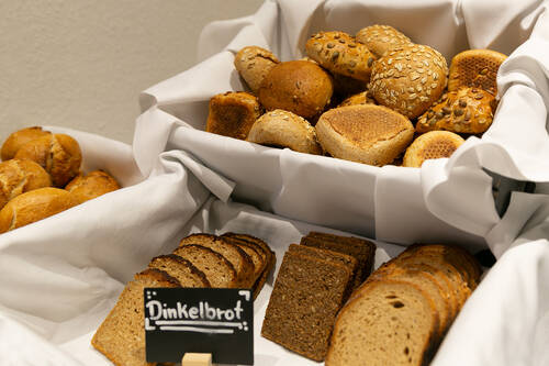 Die Auswahl an Brot und Brötchen auf dem Frühstücksbuffet. In verschiedenen Körben, die mit weißen Tüchern ausgelegt sind, befinden sich unterschiedliche Brotsorten und Brötchen.